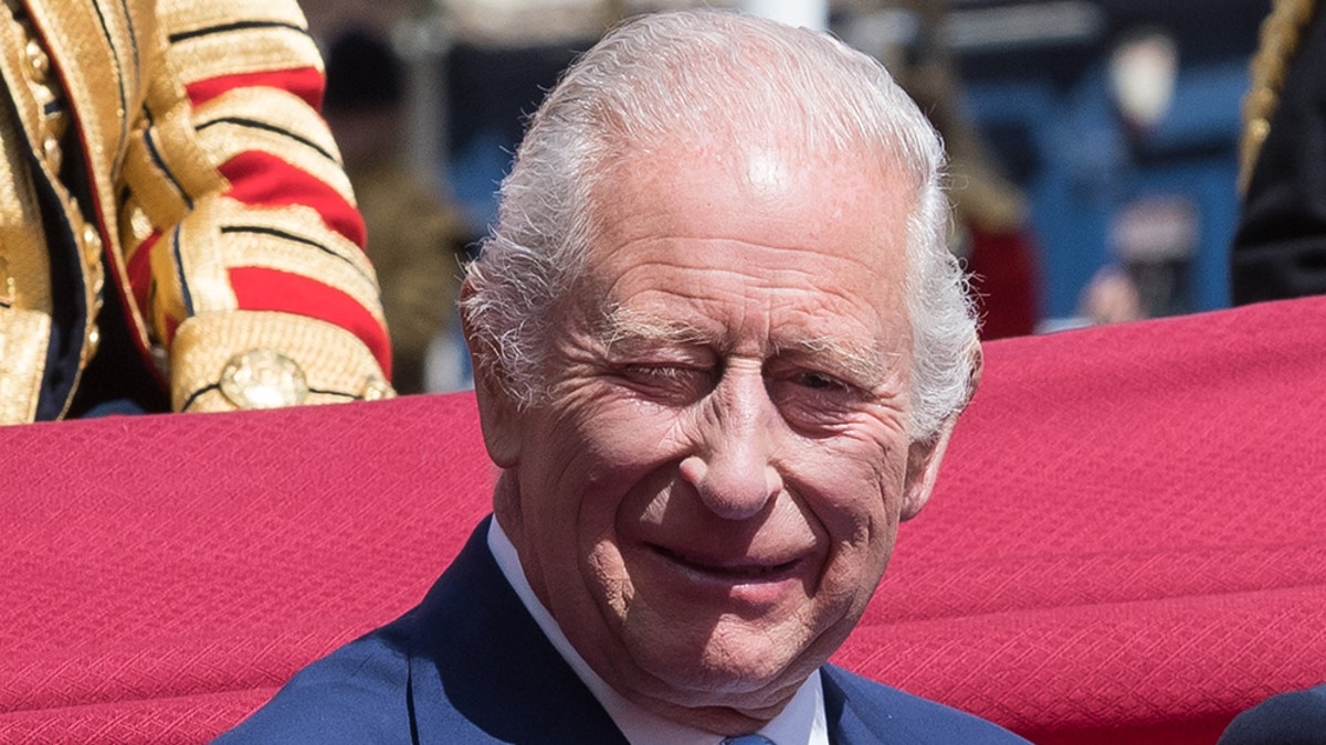 King Charles smiling in a carriage.